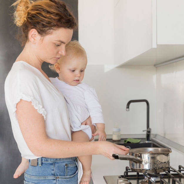 Mother cooking while holding baby girl