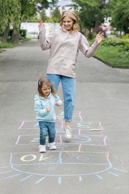 Mother and cute child playing hopscotch