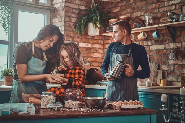 Free photo mother and daughter are cooking something tasty while father is preparing morning coffee.