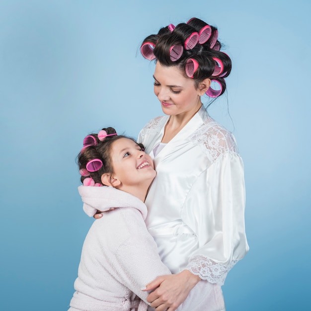 Free photo mother and daughter in bathrobes and curlers hugging