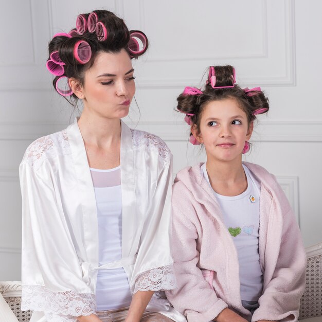 Mother and daughter in curlers looking at each other