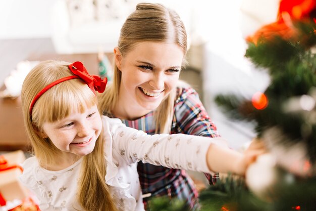 Mother and daughter decorating christmas tree together