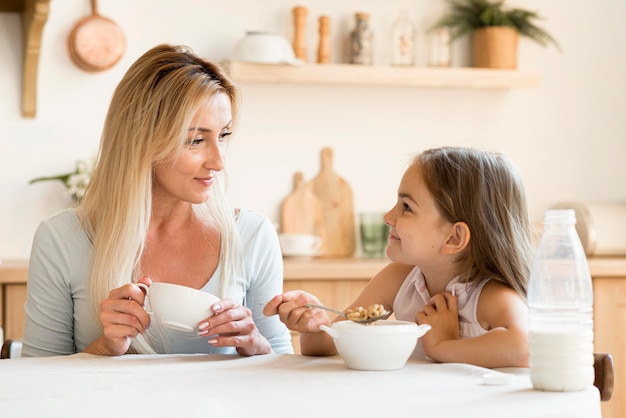 Free photo mother and daughter eating breakfast together