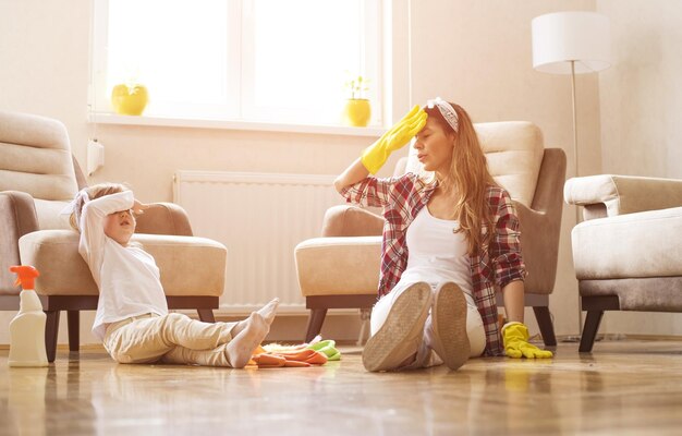 Mother and a daughter feeling exhausted after cleaning home together