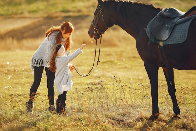 Free photo mother and daughter in a field playing with a horse