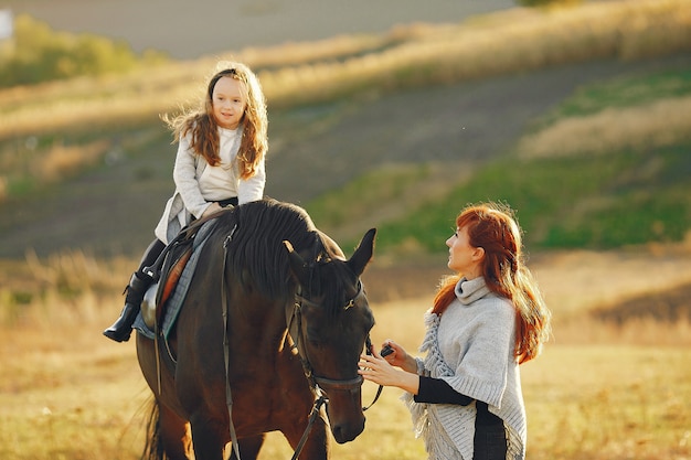 Mother and daughter in a field playing with a horse