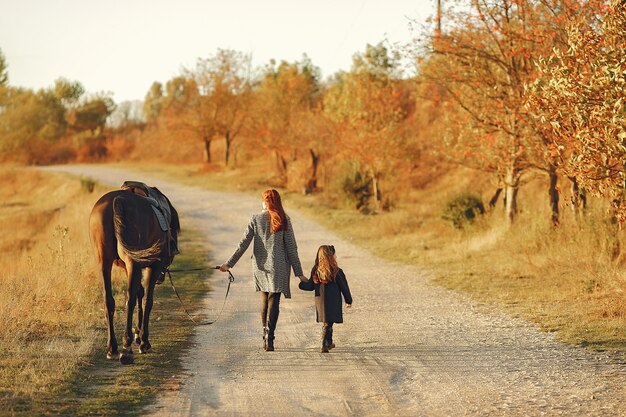 Mother and daughter in a field playing with a horse