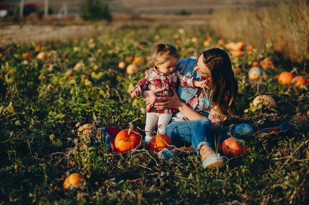 Mother and daughter on a field with pumpkins, Halloween eve