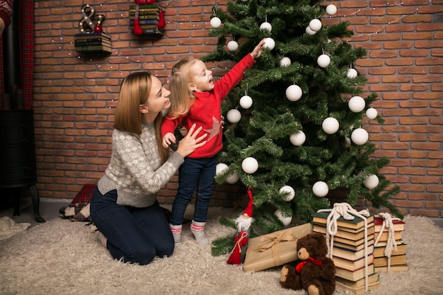 Mother and daughter hanging toys on a Christmas tree