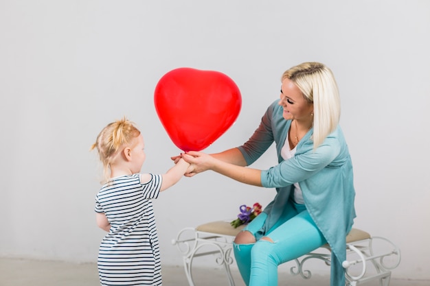 Mother and daughter holding red heart balloon