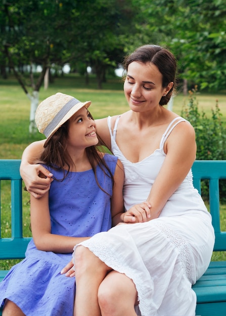 Mother and daughter hugging on bench outdoors