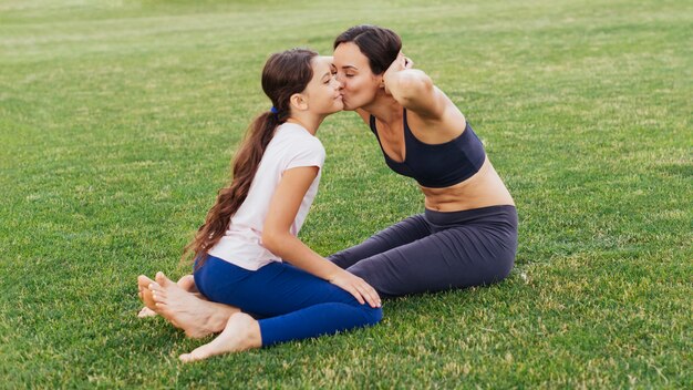 Mother and daughter kissing and exercising in nature