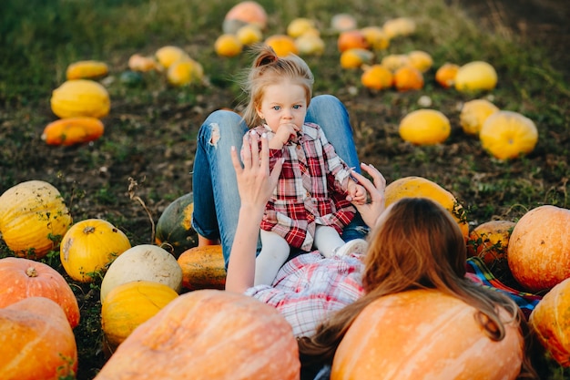 Mother and daughter lie between pumpkins on the field