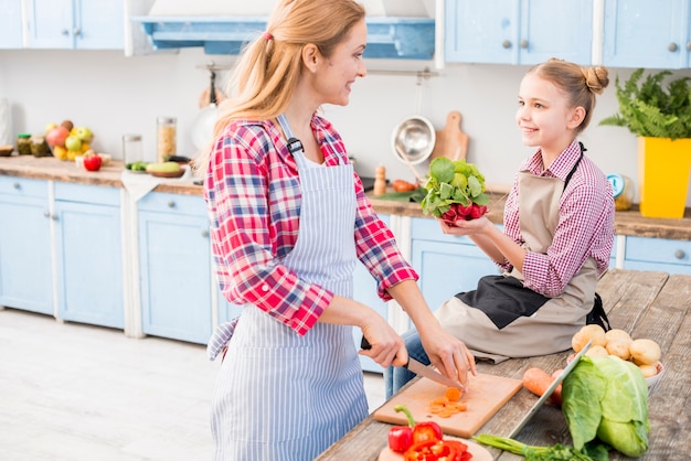 Mother and daughter looking at each other while preparing the food in the kitchen