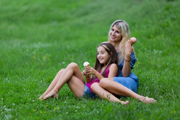 Mother and daughter lying in grass with ice cream