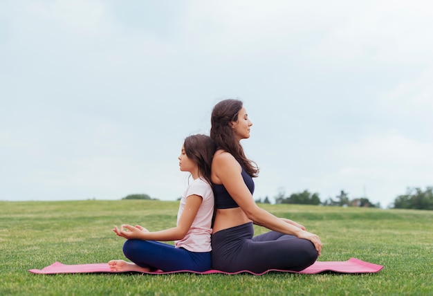 Mother and daughter meditating outdoors