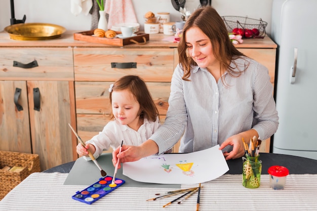 Free photo mother and daughter painting on paper