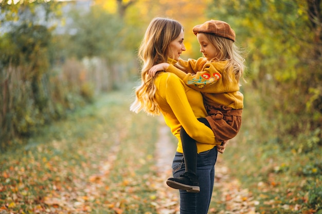 Mother and daughter in park full of leaves