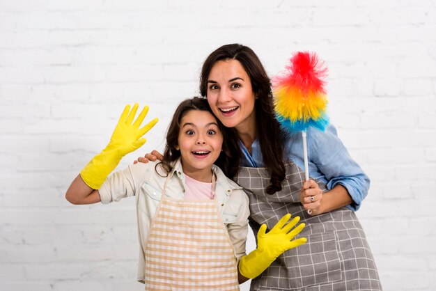 Mother and daughter posing with cleaning objects