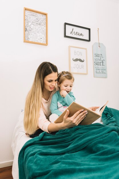 Mother and daughter reading book in bed