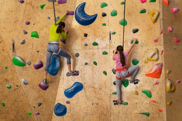 Free photo mother and daughter rock climbing together indoors at the arena