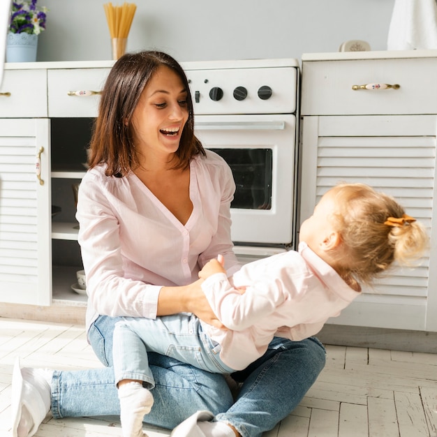 Mother and daughter sitting on kitchen floor