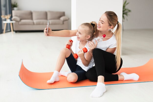 Mother and daughter taking selfie while holding weights