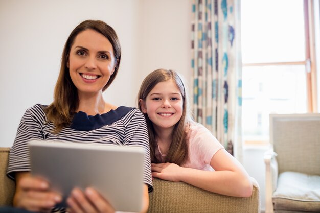 Mother and daughter using digital tablet in living room