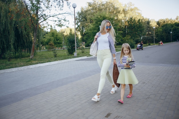 Mother and daughter walking while the girl looks at a tablet