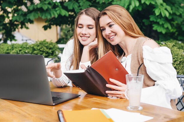 Mother and Daughter Watching into computer at outside.