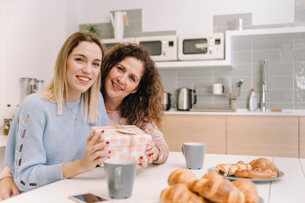 Mother and daughter with gift looking at camera