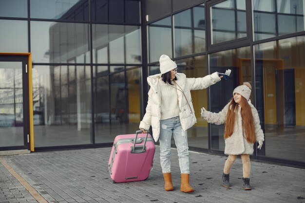 Mother and daughter with luggage going from airport terminal