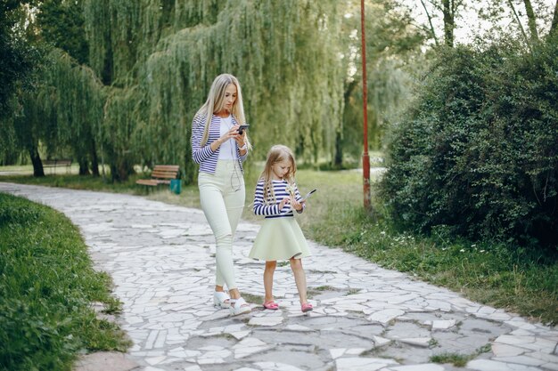 Mother and daughter with a mobile and a tablet walking in a park