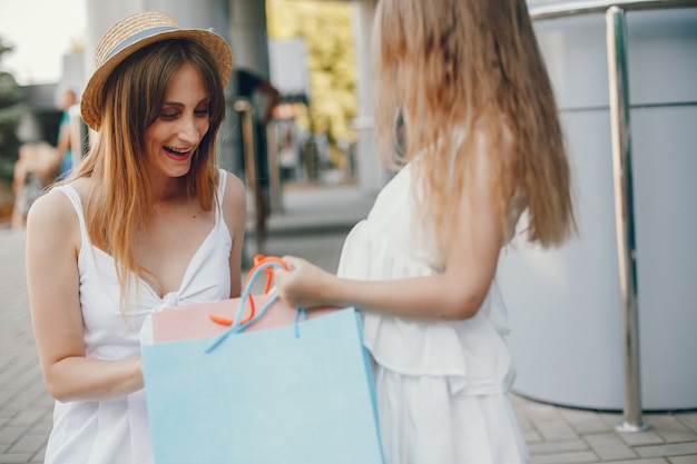 Free photo mother and daughter with shopping bag in a city