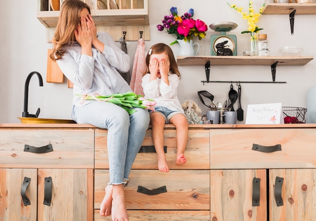 Mother and daughter with tulip flowers covering eyes