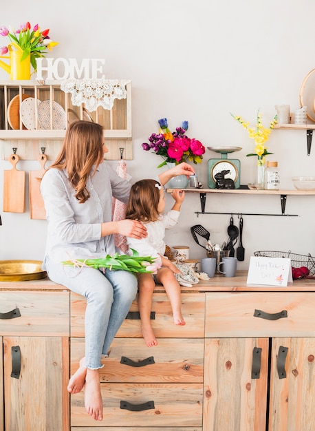 Mother and daughter with tulips sitting on table