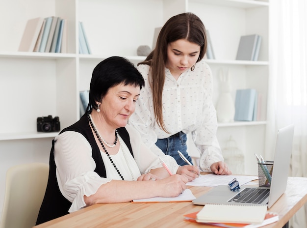 Mother and daughter writing and using a laptop