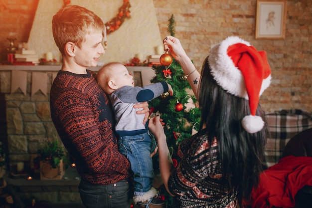 Mother distracting the baby with a christmas ornament while the father holds it in his arms