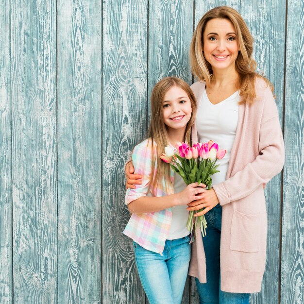 Mother embracing daughter and holding tulips