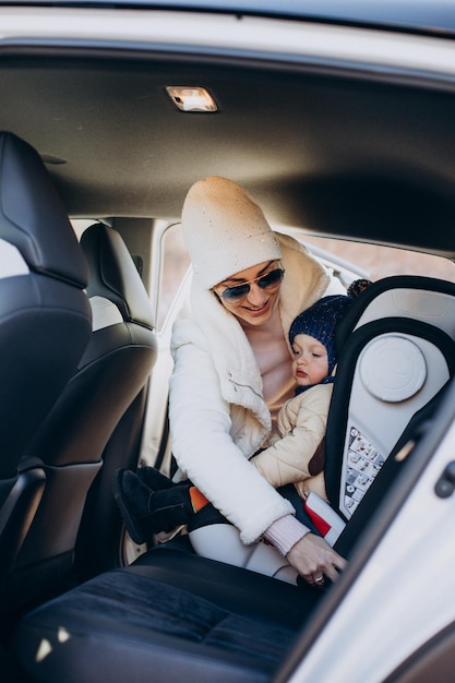 Free photo mother fastening her child in car seat