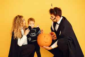 Free photo mother father and children in costumes and makeup. people standing on a yellow background.