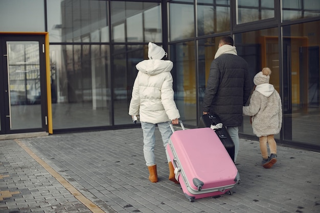 Mother father and daughter with luggage going to airport terminal