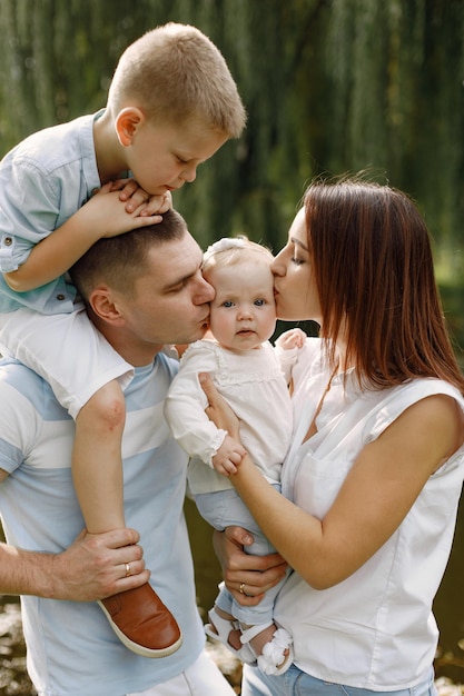 Mother, father, older son and little baby daughter walking in the park. Family wearing white and light blue clothes