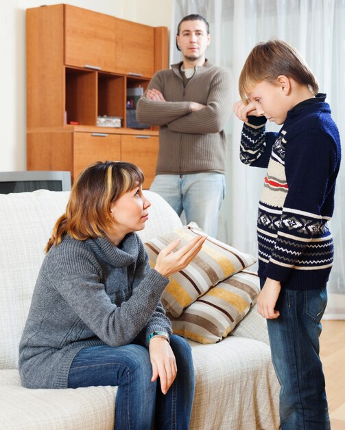 Mother and father scolding  son at living room