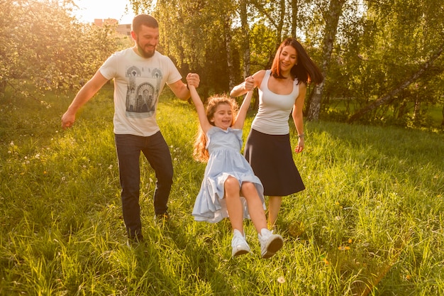 Mother and father swinging their daughter between them