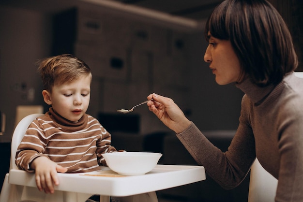 Mother feeding her baby son sitting in chair