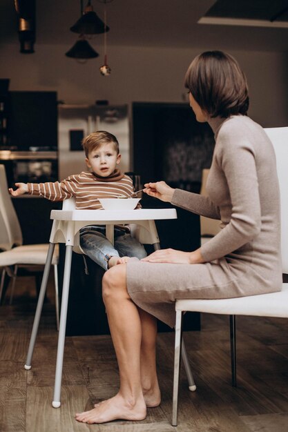 Mother feeding her baby son sitting in chair