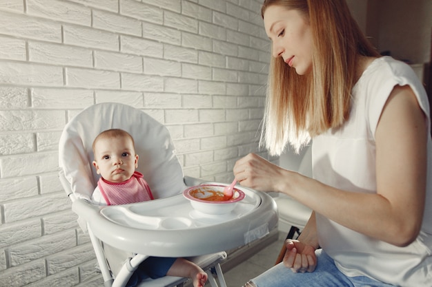 Free photo mother feeding her little baby in a kitchen