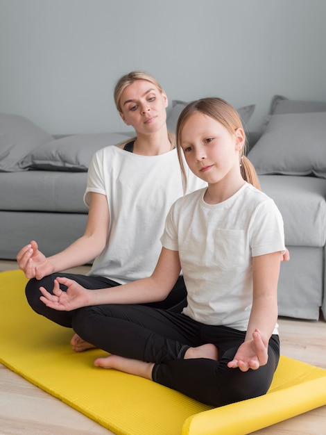 Mother and girl at home practicing yoga