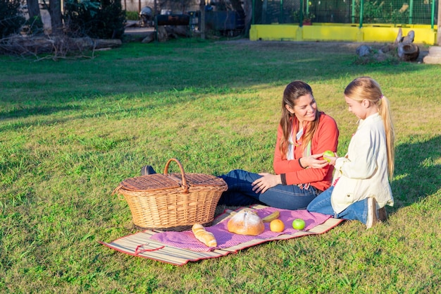 Mother giving an apple to her daughter in the park